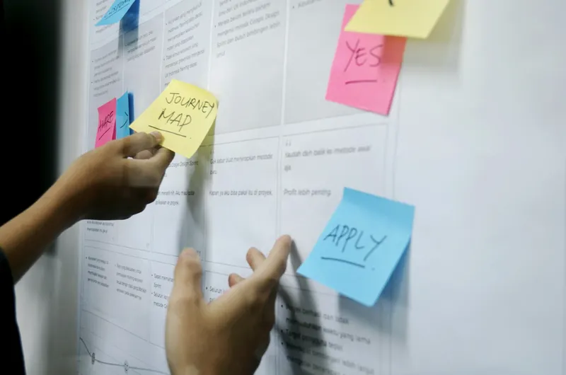 Hands mapping a workflow with colorful sticky notes.